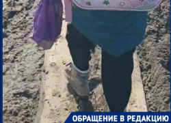 Волгоградка с дочкой по доске сквозь грязь пробираются до школы: видео